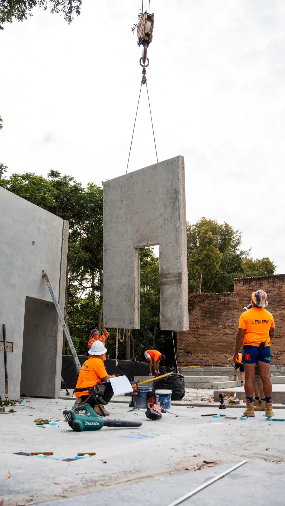 Construction crew guiding a precast concrete wall into position