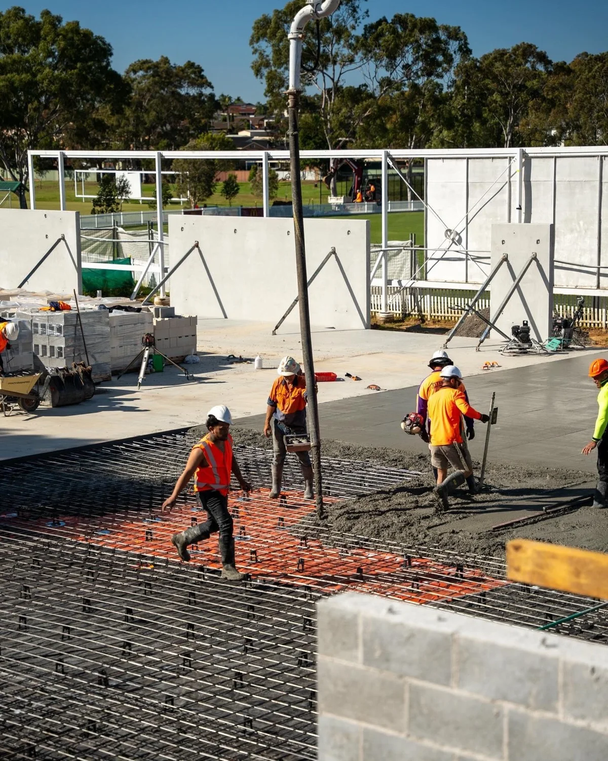 Construction crew pouring concrete over reinforcement